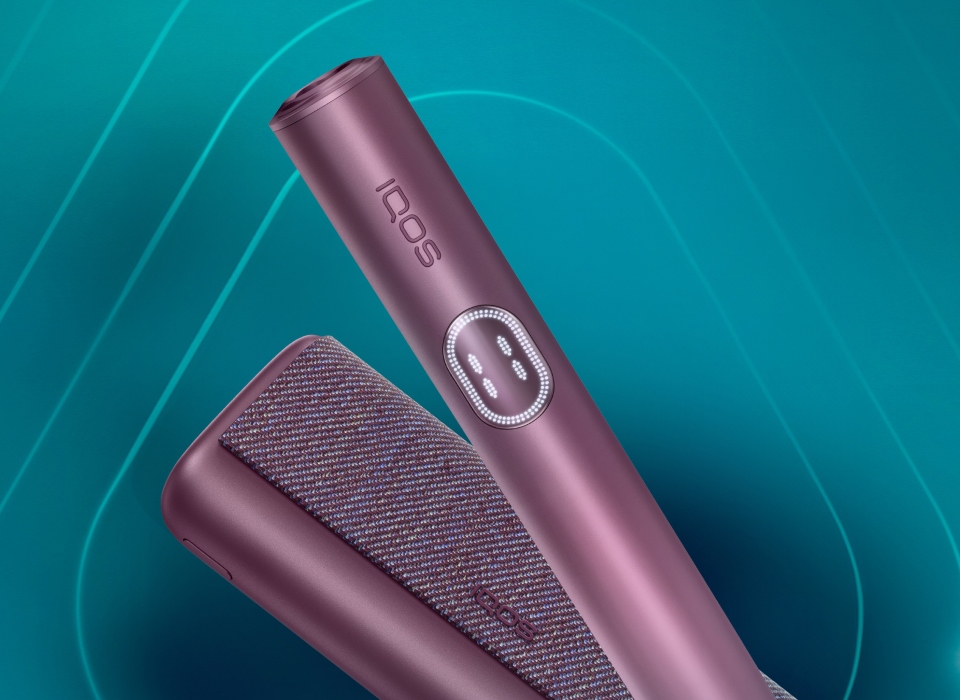 Garnet Red IQOS ILUMA i PRIME device and its charger on a dark turquoise background
